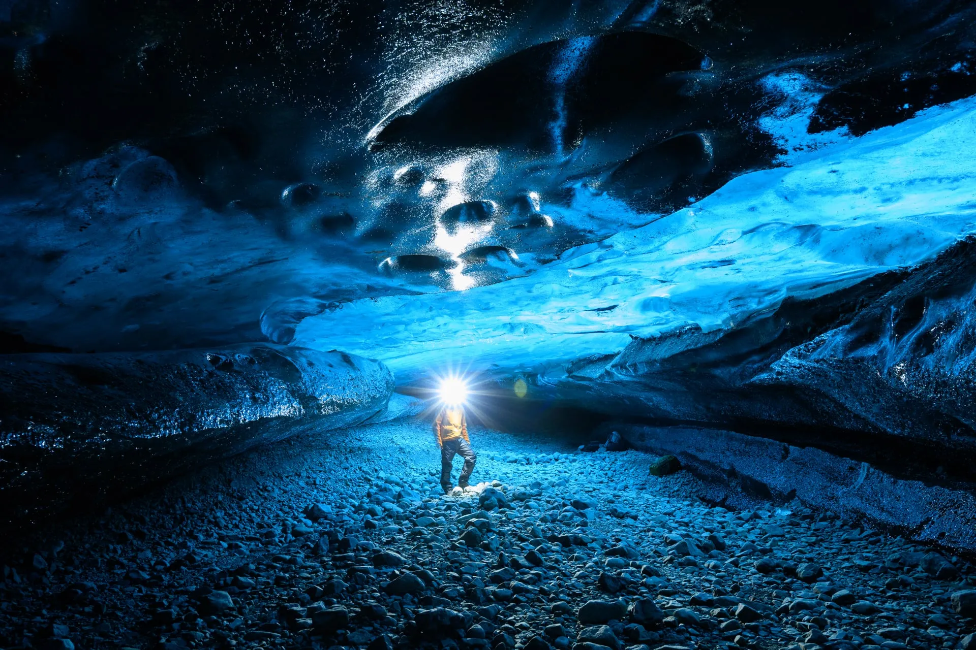 A visitor exploring a blue glacier ice cave inside Vatnajökull, Iceland