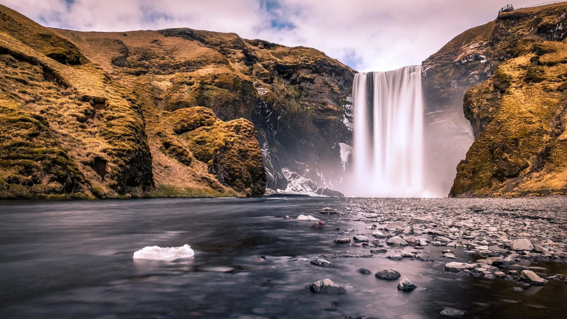Skógafoss waterfall thundering at full spring spate on the South Coast, with the surrounding cliffs greening up in April