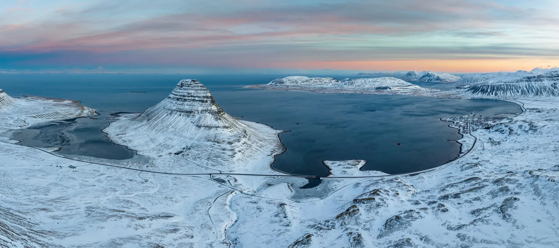 The iconic Kirkjufell mountain on the Snæfellsnes peninsula under fresh snow on a January day, with the frozen coastline below
