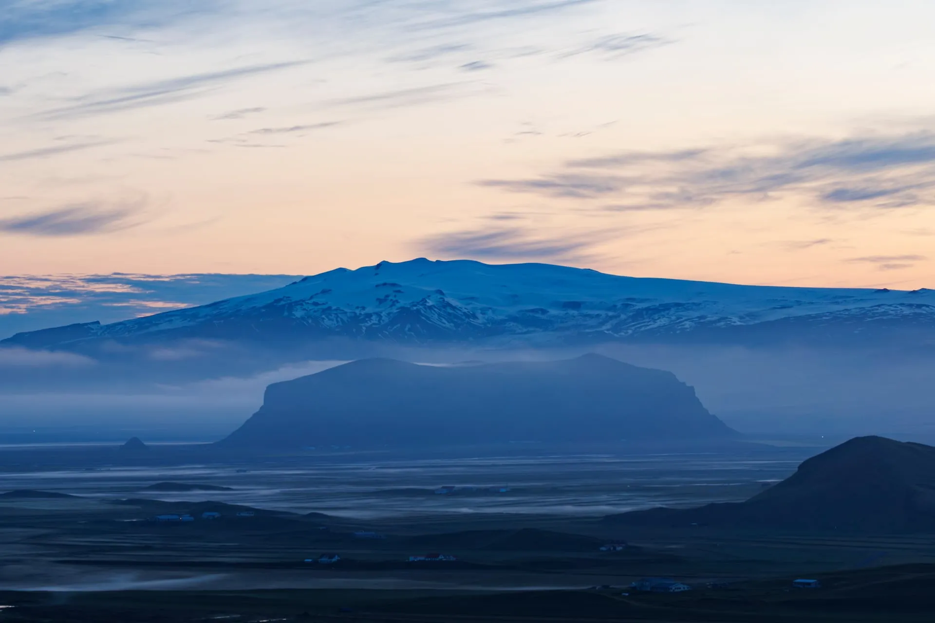 A misty green Icelandic landscape bathed in the low golden light of the midnight sun, photographed at 2am in late June