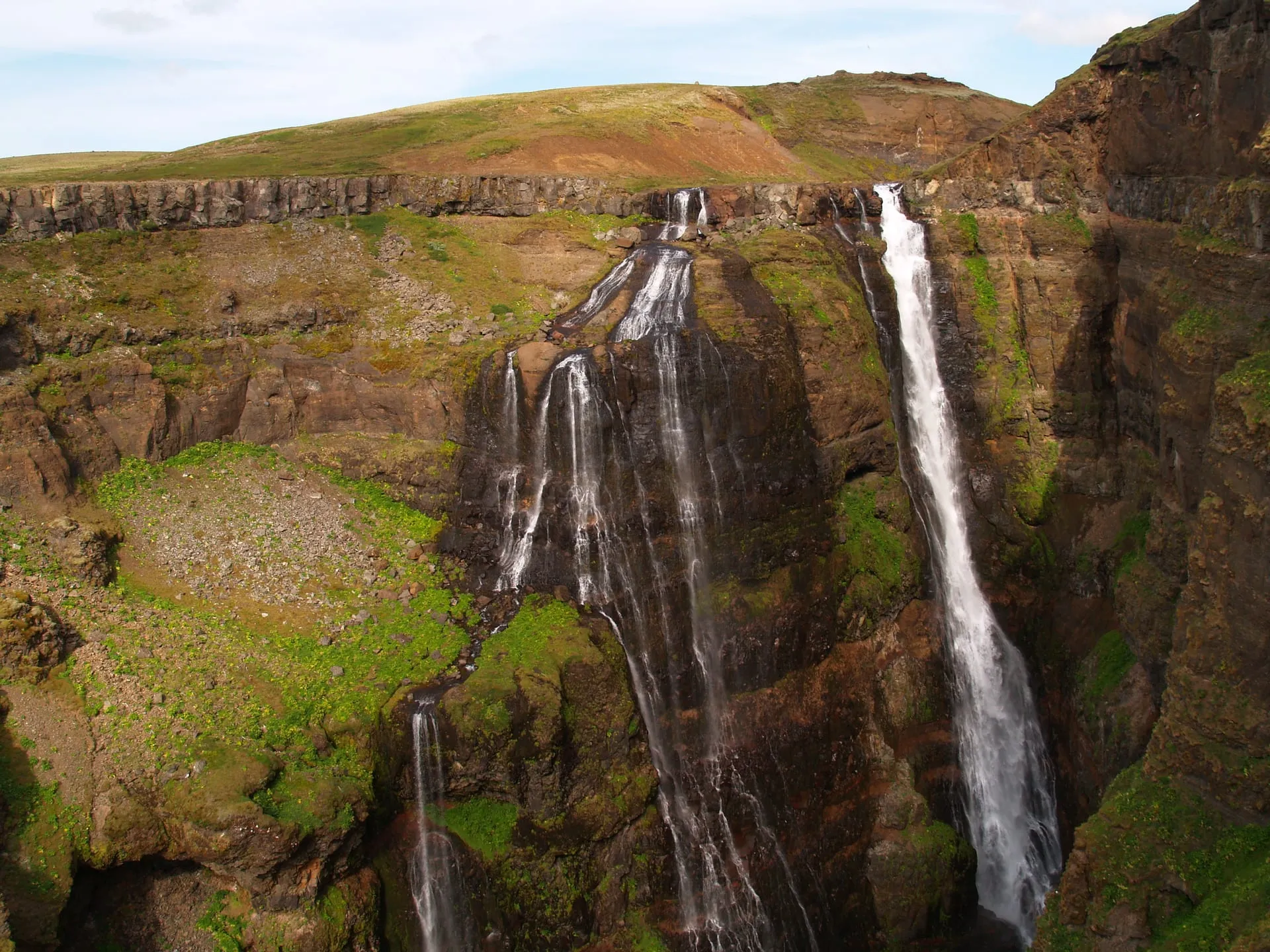 Glymur waterfall cascading down a deep moss-green gorge in south-west Iceland on a bright summer day