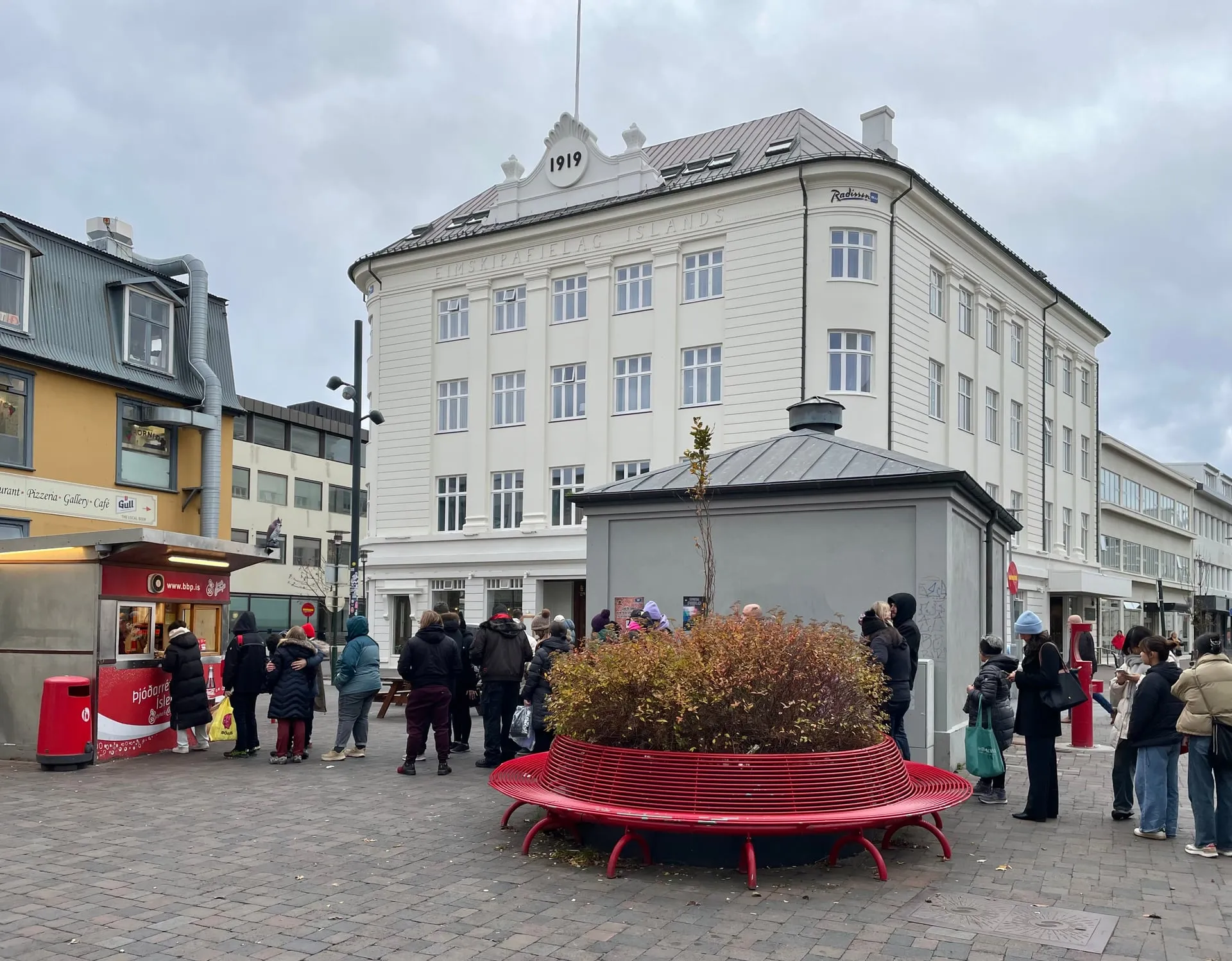 Travellers queuing at the famous red Bæjarins Beztu Pylsur hot-dog kiosk on Tryggvagata in downtown Reykjavík on an overcast day