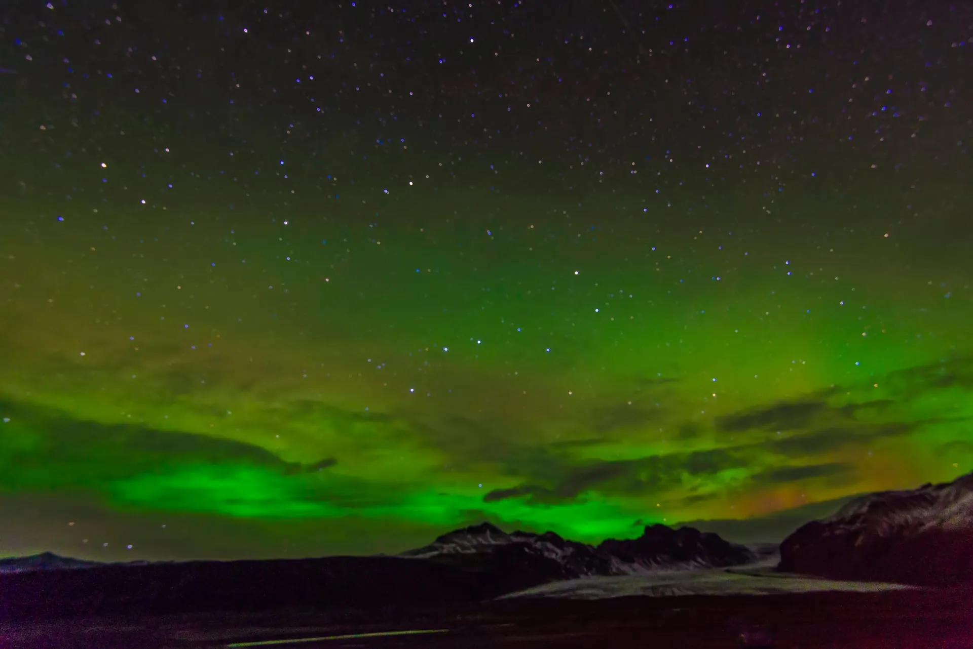 Green and purple northern lights arching across the sky over Iceland
