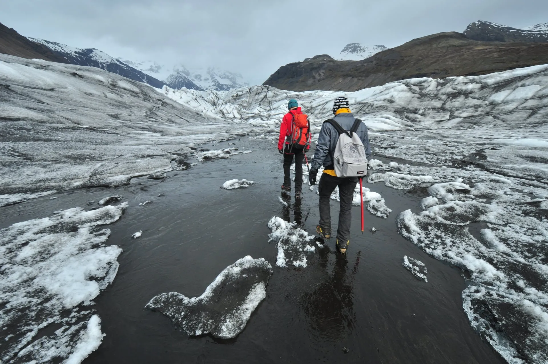 A line of hikers in crampons crossing the cracked, dirt-streaked ice of Skaftafellsjökull, an outlet glacier of Vatnajökull in southeast Iceland